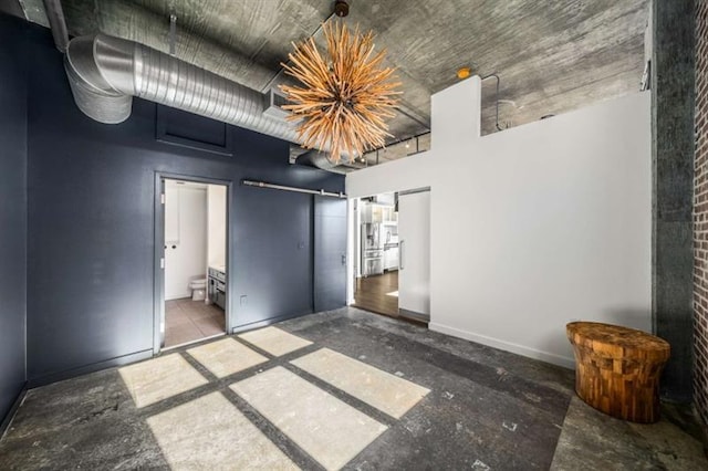 unfurnished bedroom featuring a towering ceiling, baseboards, and connected bathroom
