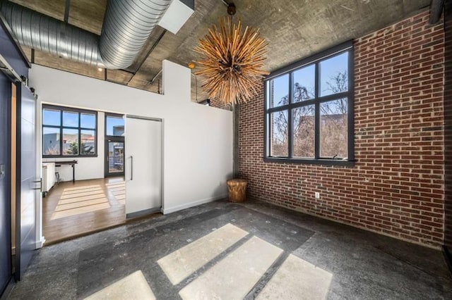 empty room featuring brick wall and a towering ceiling