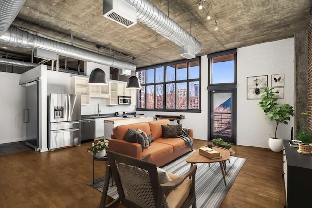 living area featuring a high ceiling, visible vents, and dark wood-type flooring
