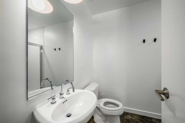 bathroom featuring baseboards, a sink, and toilet