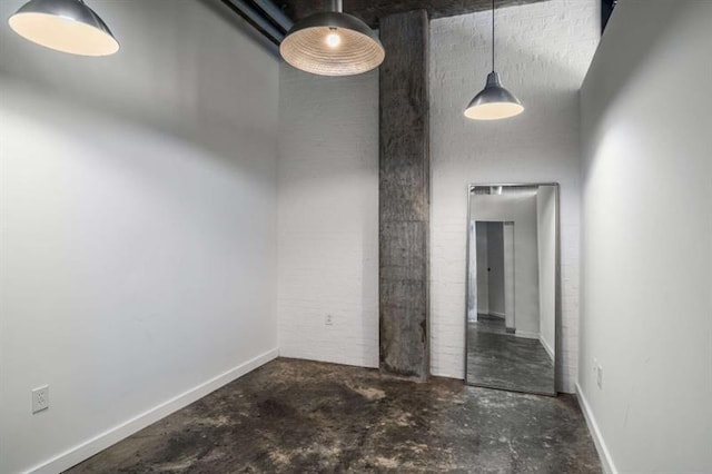 spare room with unfinished concrete flooring, a towering ceiling, and baseboards