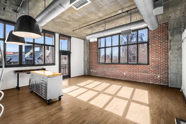 interior space with brick wall, visible vents, and wood finished floors