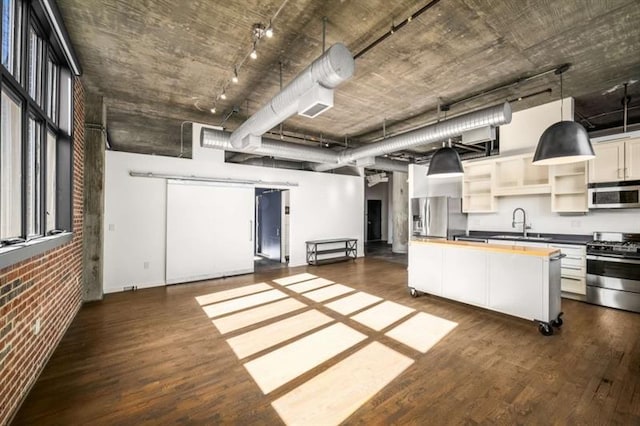 kitchen featuring dark wood finished floors, open shelves, stainless steel appliances, wooden counters, and brick wall