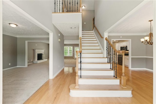 2154 Marne Gln NW, Kennesaw, GA 30152 - stairs with a fireplace with raised hearth, a textured ceiling, wood finished floors, baseboards, and crown molding