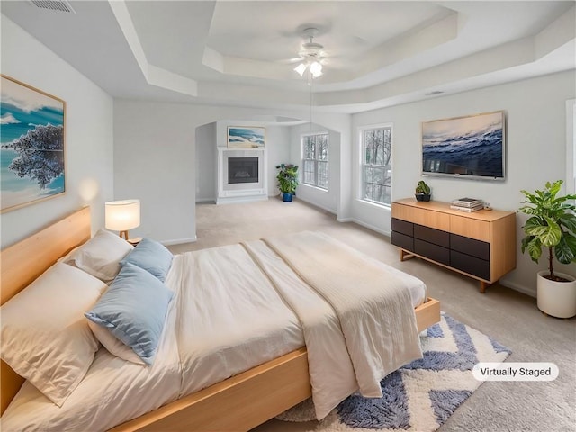 carpeted bedroom with ceiling fan and a tray ceiling