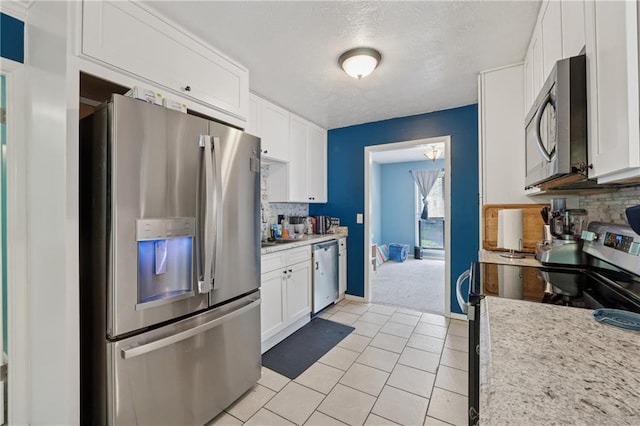 5360 Fieldgreen Dr, Stone Mountain, GA 30088 - kitchen with appliances with stainless steel finishes, tasteful backsplash, white cabinetry, light countertops, and a textured ceiling