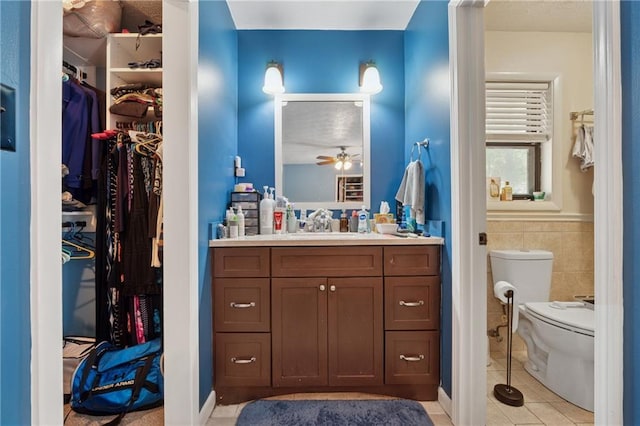 5360 Fieldgreen Dr, Stone Mountain, GA 30088 - full bathroom with vanity, a ceiling fan, tile patterned floors, a spacious closet, and tile walls