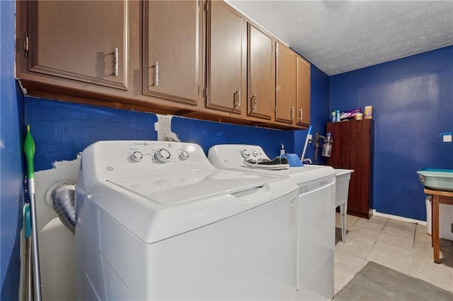 5360 Fieldgreen Dr, Stone Mountain, GA 30088 - laundry room featuring washing machine and clothes dryer, cabinet space, a textured ceiling, and light tile patterned floors