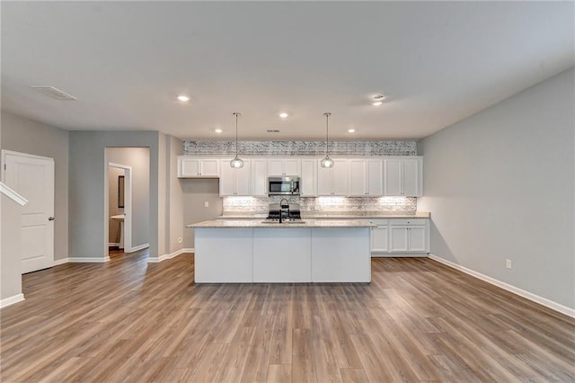 kitchen with a center island with sink, light wood-type flooring, and white cabinets