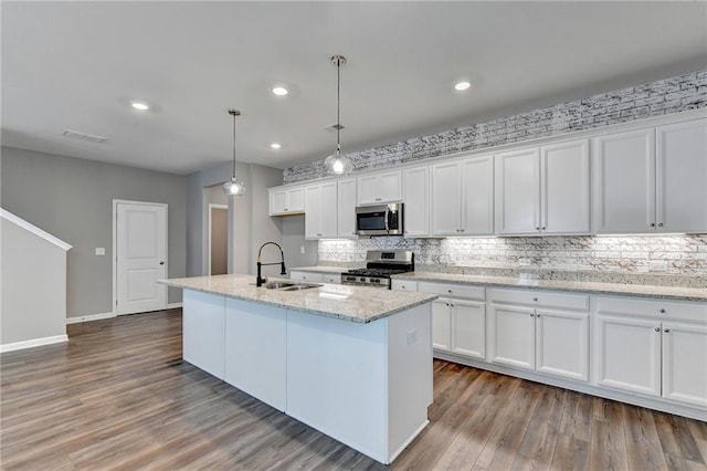 kitchen with pendant lighting, sink, an island with sink, appliances with stainless steel finishes, and white cabinetry