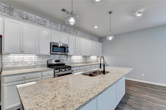 kitchen featuring hanging light fixtures, sink, a center island with sink, white cabinetry, and appliances with stainless steel finishes