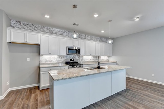 kitchen featuring pendant lighting, a center island with sink, white cabinets, and appliances with stainless steel finishes