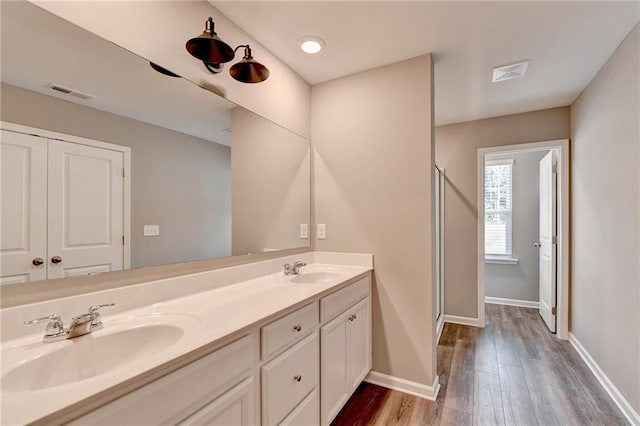 bathroom with wood-type flooring, a shower with door, and vanity