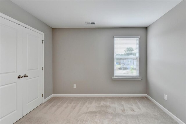 unfurnished bedroom with a closet and light colored carpet