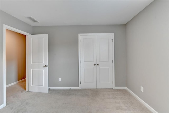 unfurnished bedroom featuring light carpet and a closet