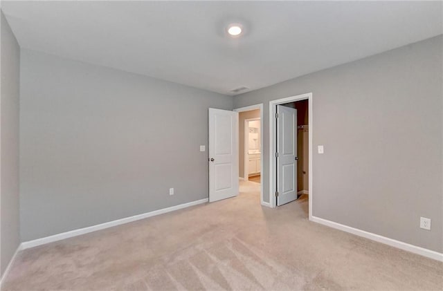 unfurnished bedroom featuring light colored carpet, a closet, and a walk in closet