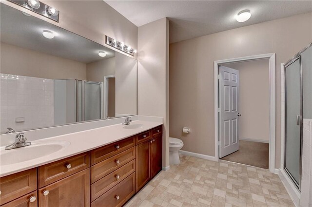 3500 Sweetwater Rd Unit 522, Duluth, GA 30096 - bathroom featuring a shower stall, double vanity, baseboards, and toilet