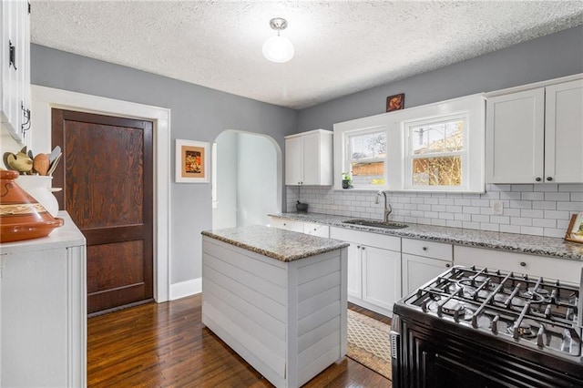 kitchen featuring light stone countertops, sink, stainless steel stove, white cabinetry, and dark hardwood / wood-style floors