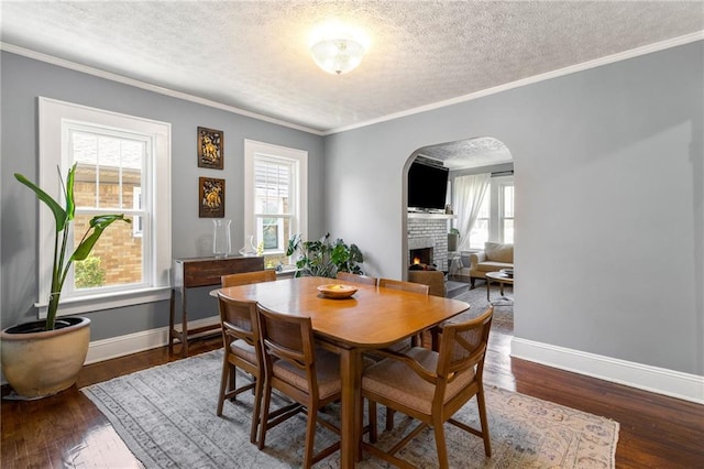 dining room featuring dark hardwood / wood-style flooring, plenty of natural light, a textured ceiling, and ornamental molding