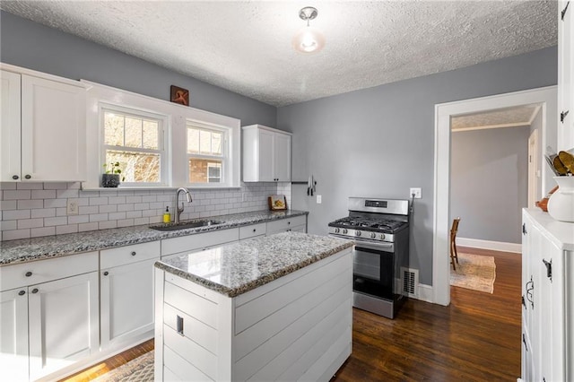 kitchen featuring white cabinetry, stainless steel gas stove, dark wood-type flooring, and sink