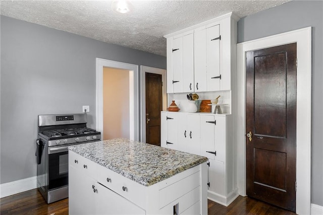 kitchen featuring a textured ceiling, stainless steel gas stove, dark hardwood / wood-style floors, and white cabinetry