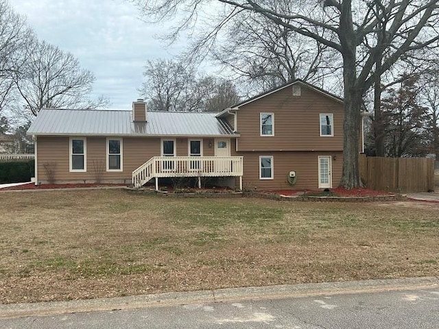 rear view of property with a wooden deck and a lawn