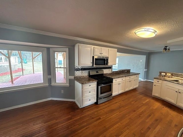 kitchen with white cabinetry, dark hardwood / wood-style flooring, stainless steel appliances, and ornamental molding