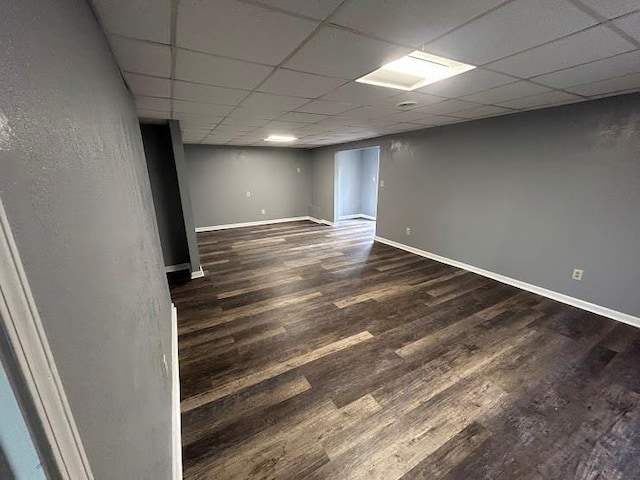 basement featuring a drop ceiling and dark wood-type flooring