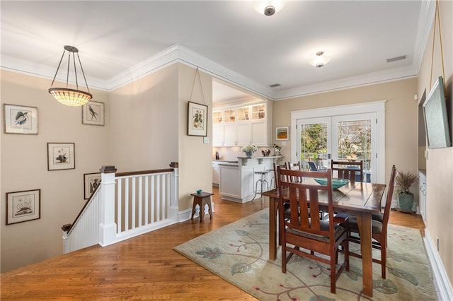 dining space with crown molding, french doors, and hardwood / wood-style flooring