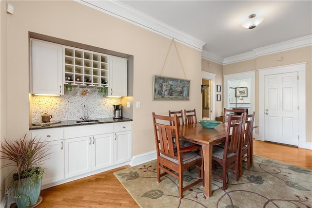 dining area with ornamental molding, sink, and light hardwood / wood-style floors