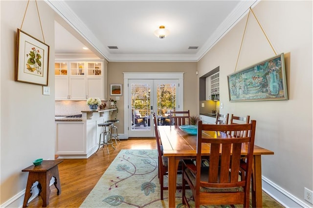 dining space featuring light hardwood / wood-style floors, ornamental molding, and french doors