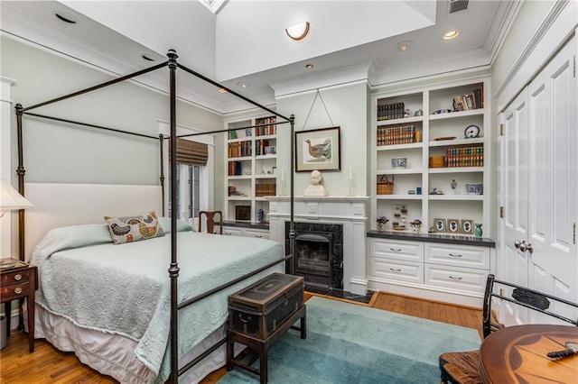 bedroom with dark hardwood / wood-style floors, a premium fireplace, and crown molding