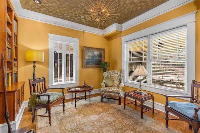 living area featuring crown molding, wood-type flooring, and a notable chandelier