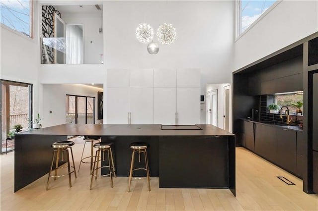 2125 Datona Dr SW, Atlanta, GA 30331 - kitchen with a high ceiling, modern cabinets, dark countertops, white cabinets, and light wood finished floors