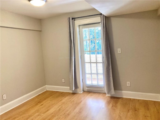 empty room featuring light wood-type flooring and baseboards