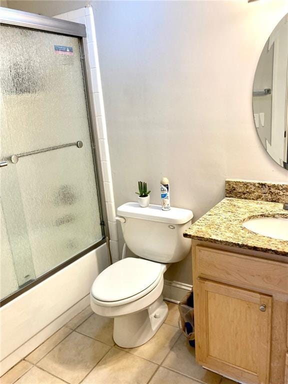 bathroom with tile patterned flooring, toilet, vanity, and shower / bath combination with glass door