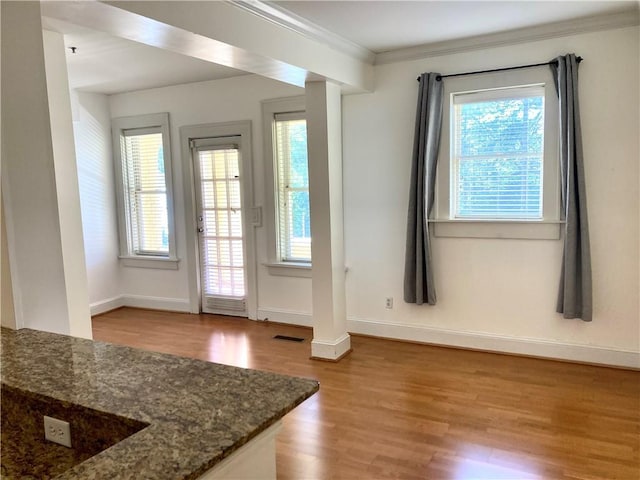 doorway featuring crown molding, wood finished floors, visible vents, and baseboards