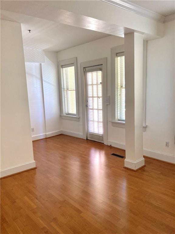 interior space featuring visible vents, crown molding, baseboards, and wood finished floors