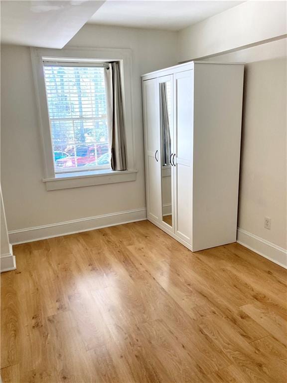 unfurnished bedroom featuring a closet, baseboards, and light wood finished floors