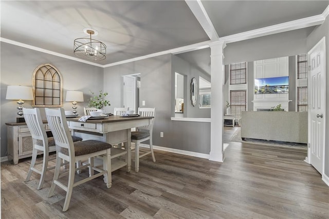 dining area with wood-type flooring, a notable chandelier, crown molding, and decorative columns