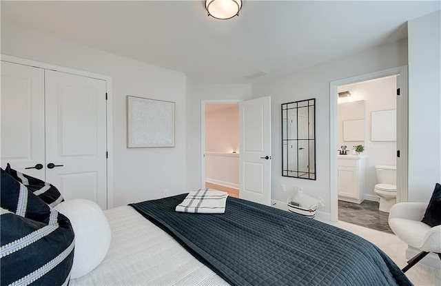 bedroom featuring a closet, ensuite bath, and baseboards