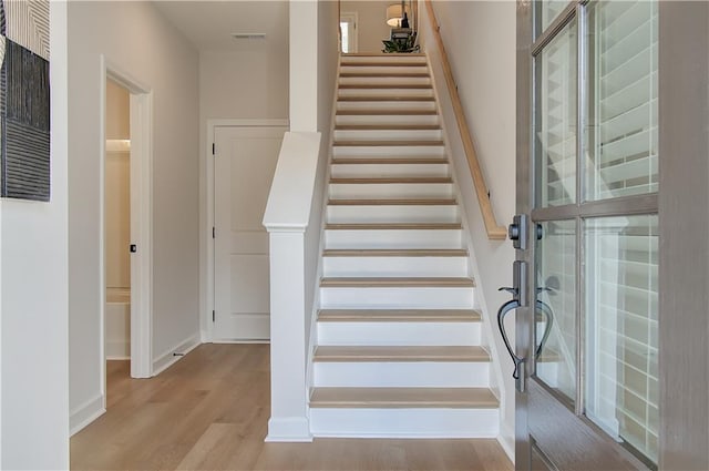 stairway with visible vents, baseboards, and wood finished floors