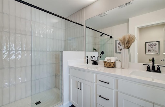 full bath featuring a sink, visible vents, a stall shower, and double vanity