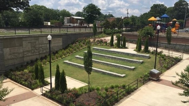 view of community with a lawn, playground community, and fence