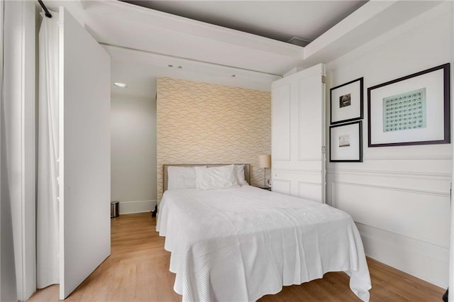 75 Ponce De Leon Ave NE Unit 1006, Atlanta, GA 30308 - bedroom featuring wallpapered walls, an accent wall, and light wood-style flooring