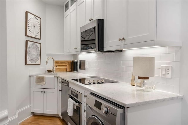 75 Ponce De Leon Ave NE Unit 1006, Atlanta, GA 30308 - kitchen with washer / clothes dryer, appliances with stainless steel finishes, tasteful backsplash, and white cabinetry