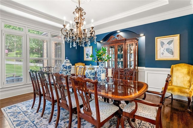 dining space with a chandelier, wood finished floors, a wainscoted wall, and crown molding