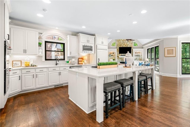 kitchen featuring stainless steel appliances, a kitchen bar, a kitchen island, dark wood finished floors, and recessed lighting