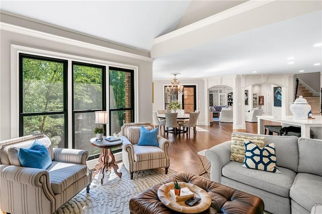 living room with a chandelier, vaulted ceiling, wood finished floors, arched walkways, and ornamental molding