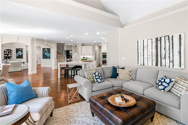 living room featuring wood finished floors, lofted ceiling, arched walkways, recessed lighting, and decorative columns